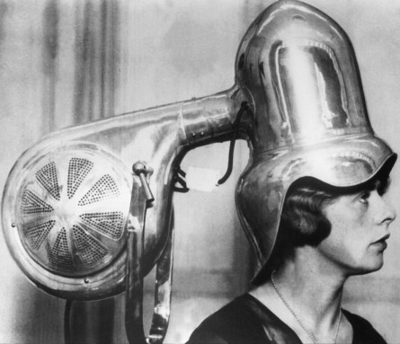 Metallic hair-dryer, with a young woman underneath, in the 1930's. Séchoir à cheveux métallique, avec une jeune femme en dessous, dans les années 1930.